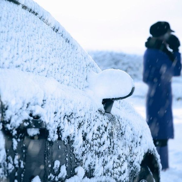 woman standing next to a car covered in snow