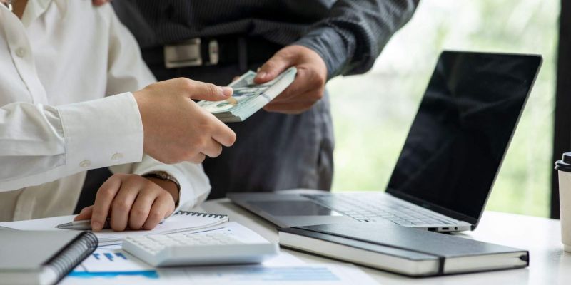 Two people review insurance payout details on a laptop and