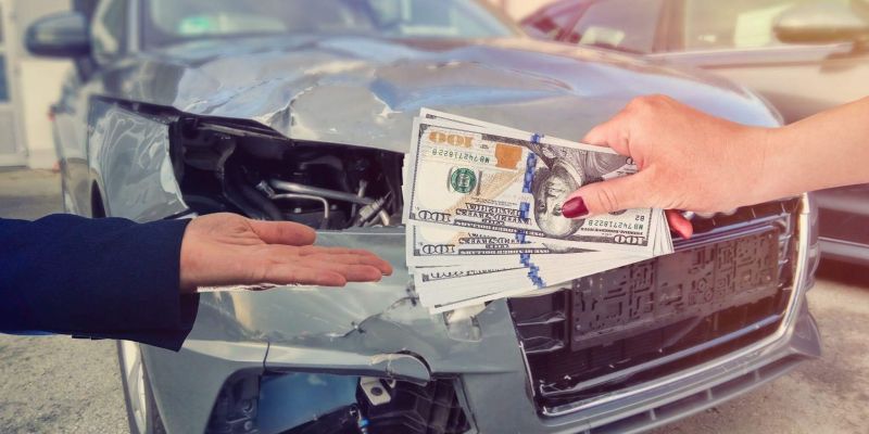 a person holding money over the front of a car, the car is damaged