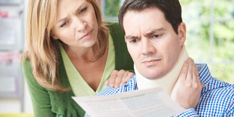 a man with a neck brace and a woman looking at a piece of paper