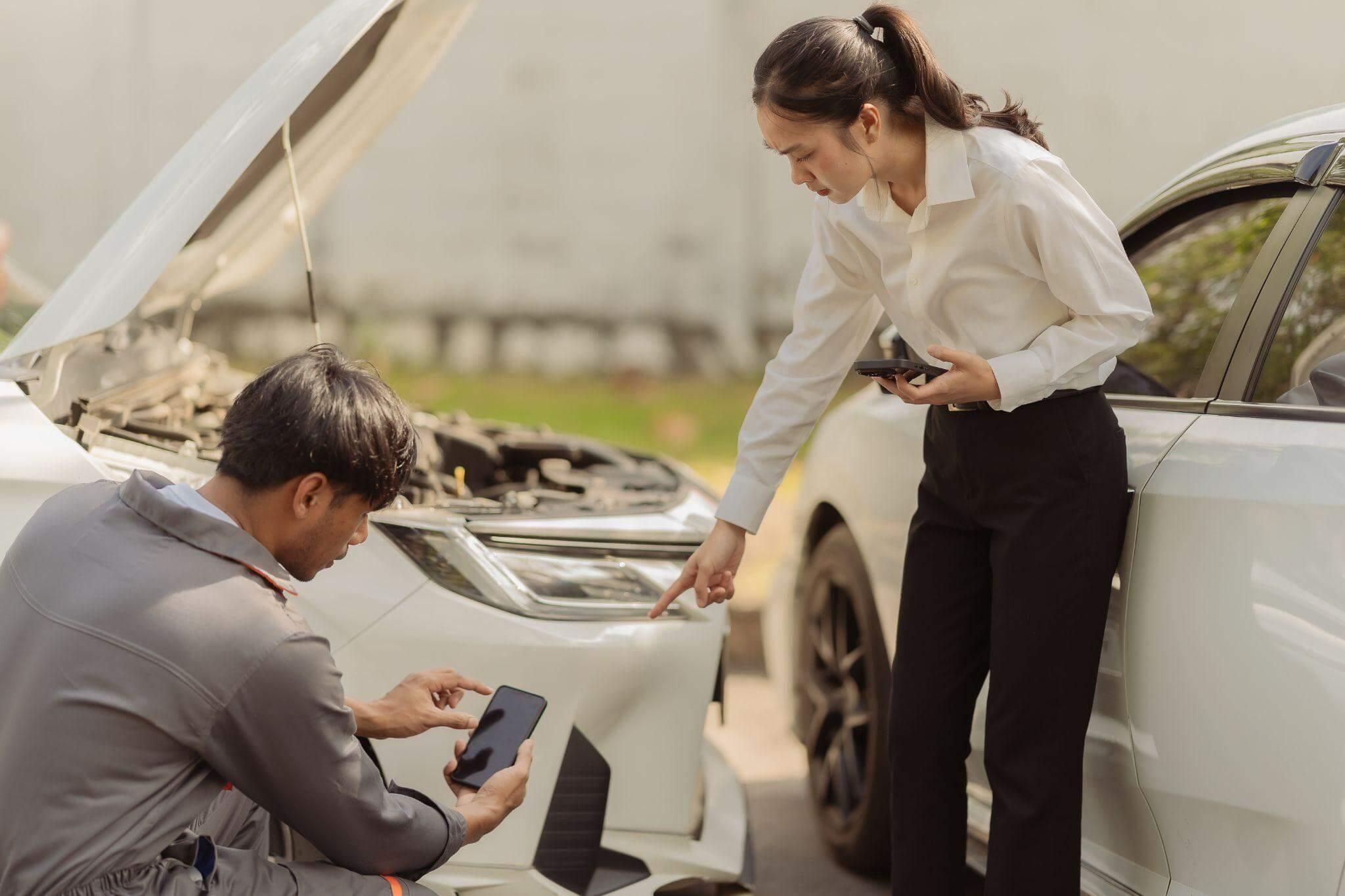 a woman looking at a tablet next to a car