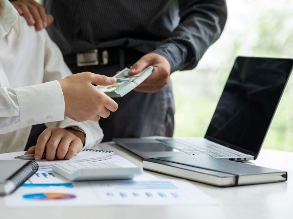 Two people review insurance payout details on a laptop and