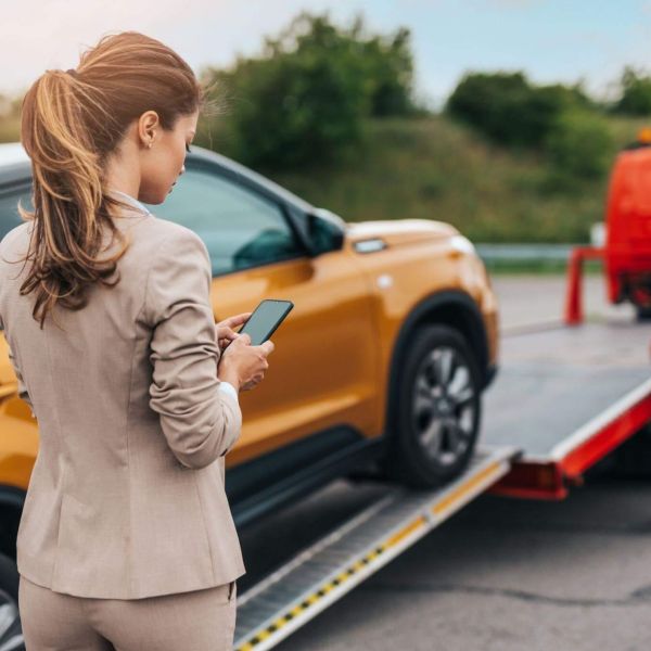 a woman standing next to a car on a tow truck