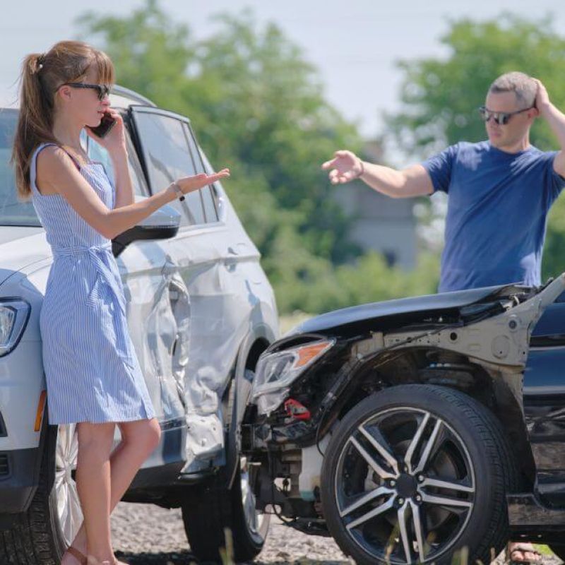 image of two people outside their vehicles on a roadway after an accident, both frustrated