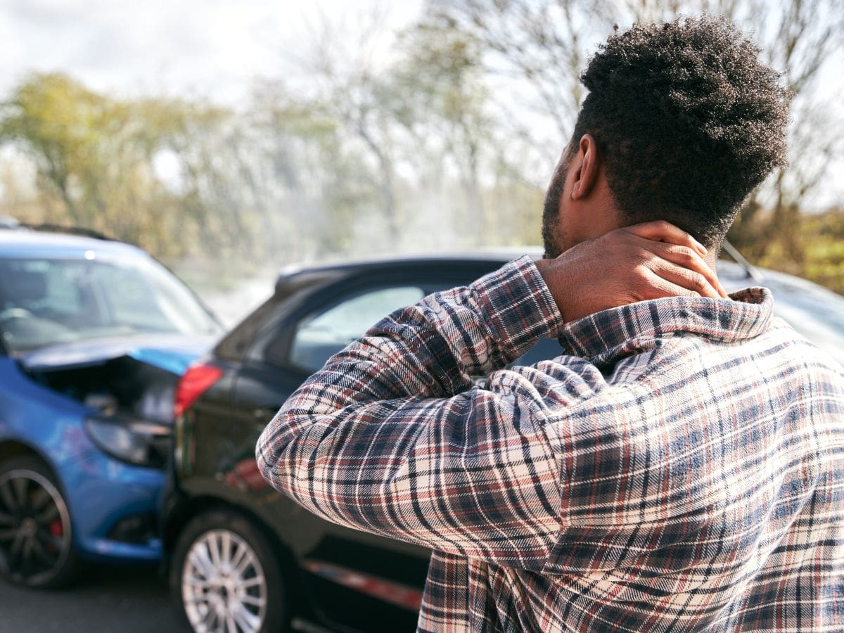 Man holding neck looking at auto accident