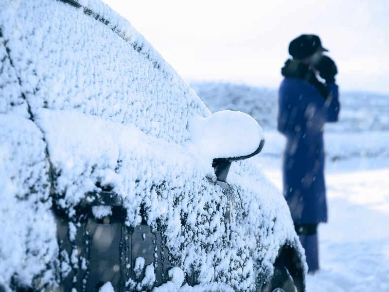 woman standing next to a car covered in snow 