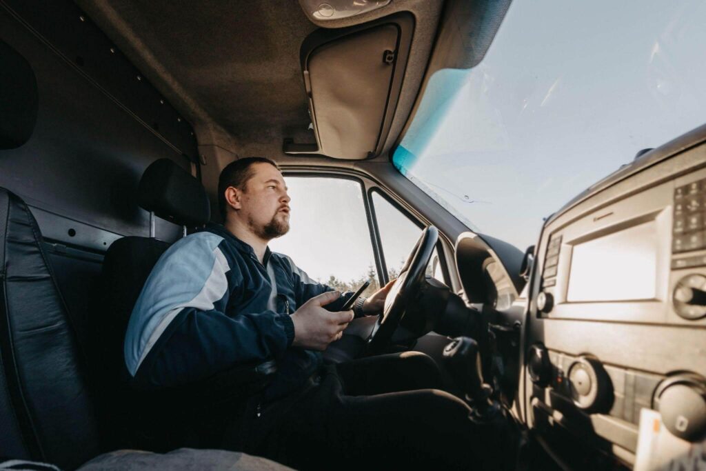 a man sitting in the driver's seat of a truck with a cellphone in his hand
