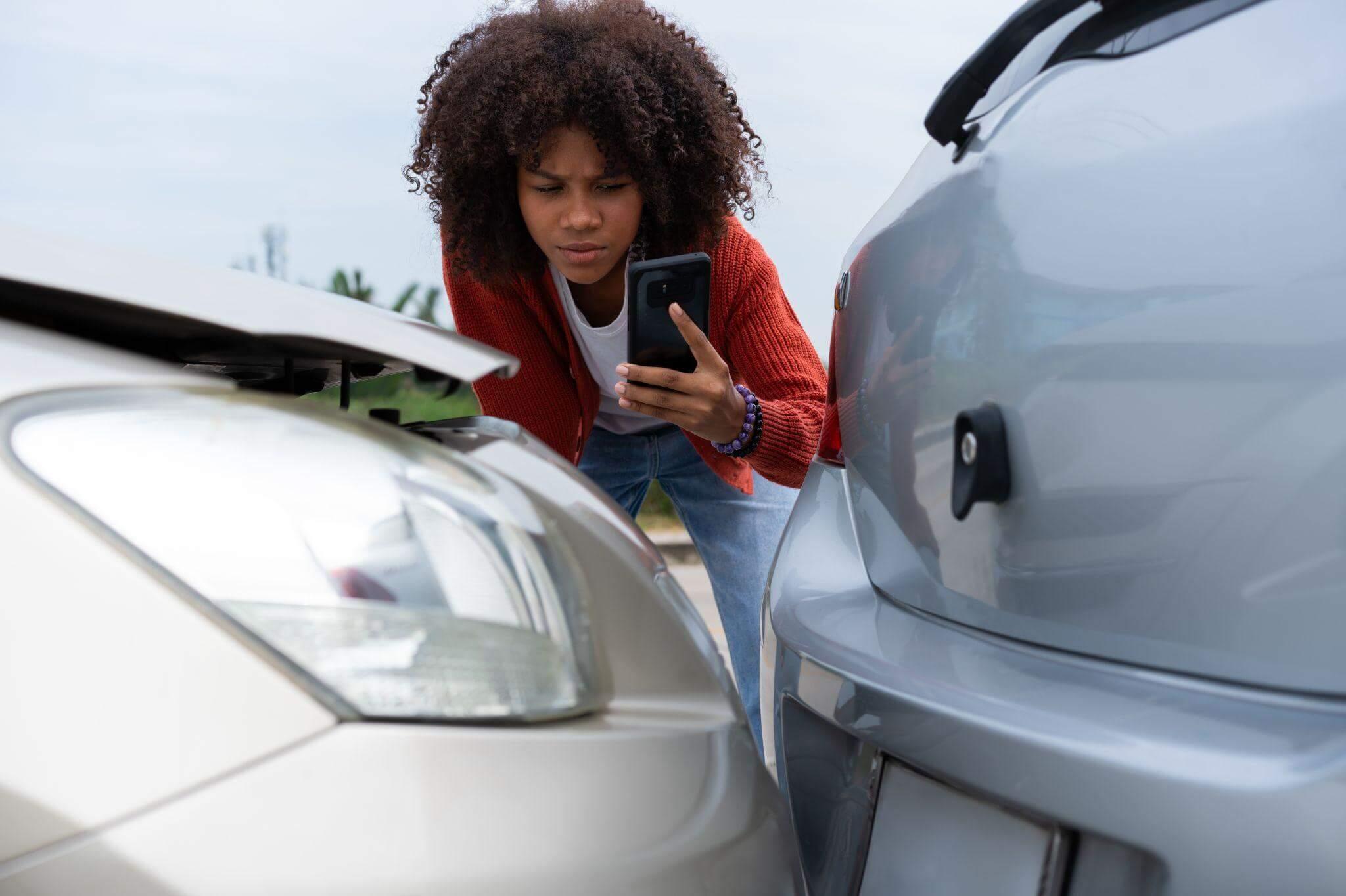 a woman looking at her cell phone next to a car