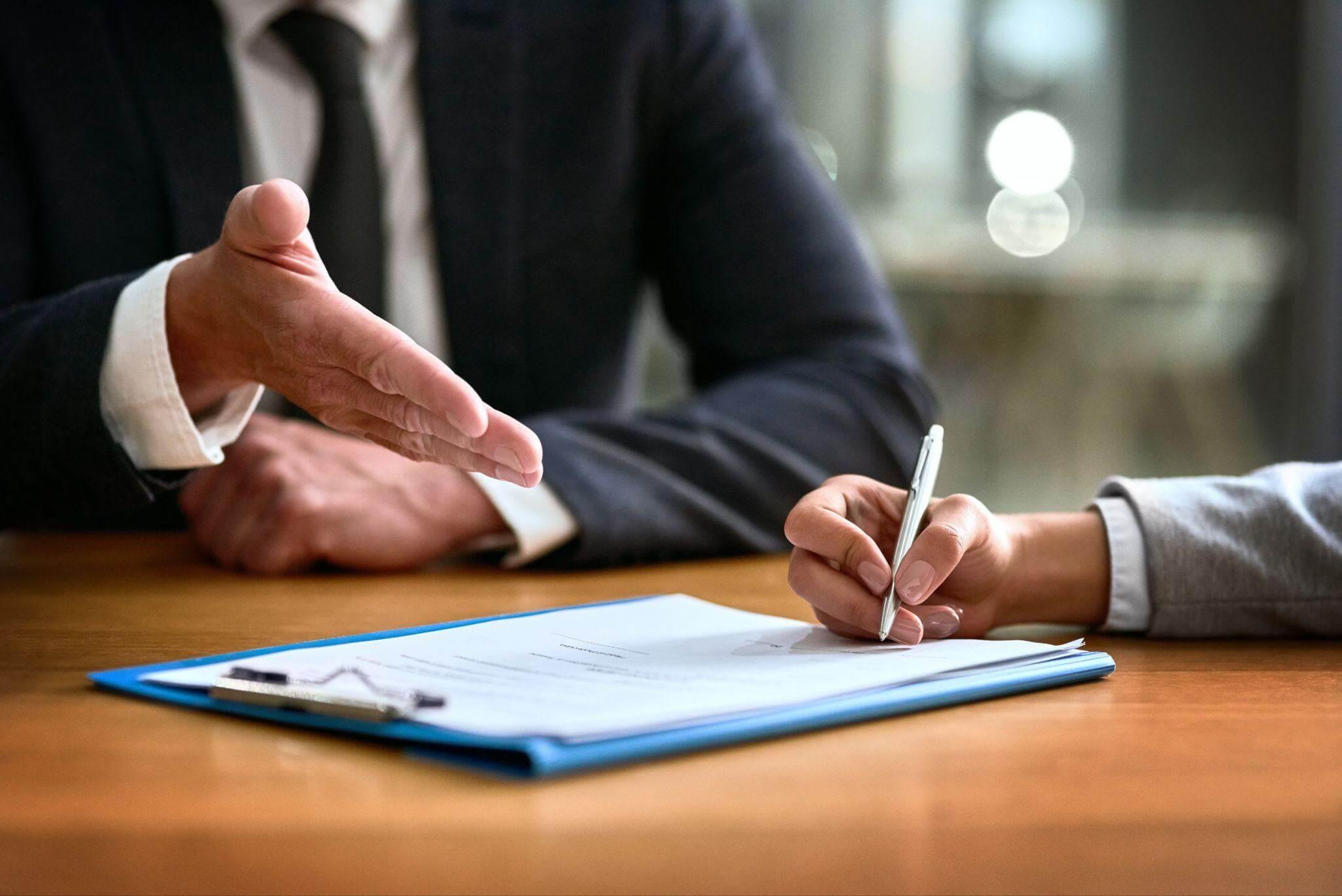 two people sitting at a table with a pen and paper